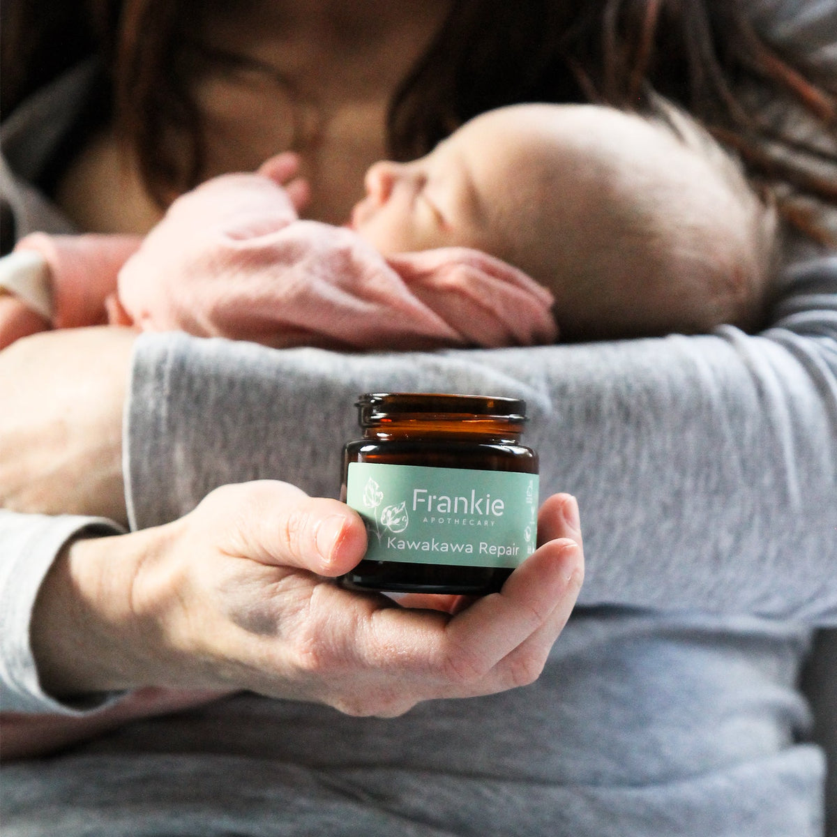 Mum gently holding her newborn baby, natural Kawakawa Balm, skin care NZ.